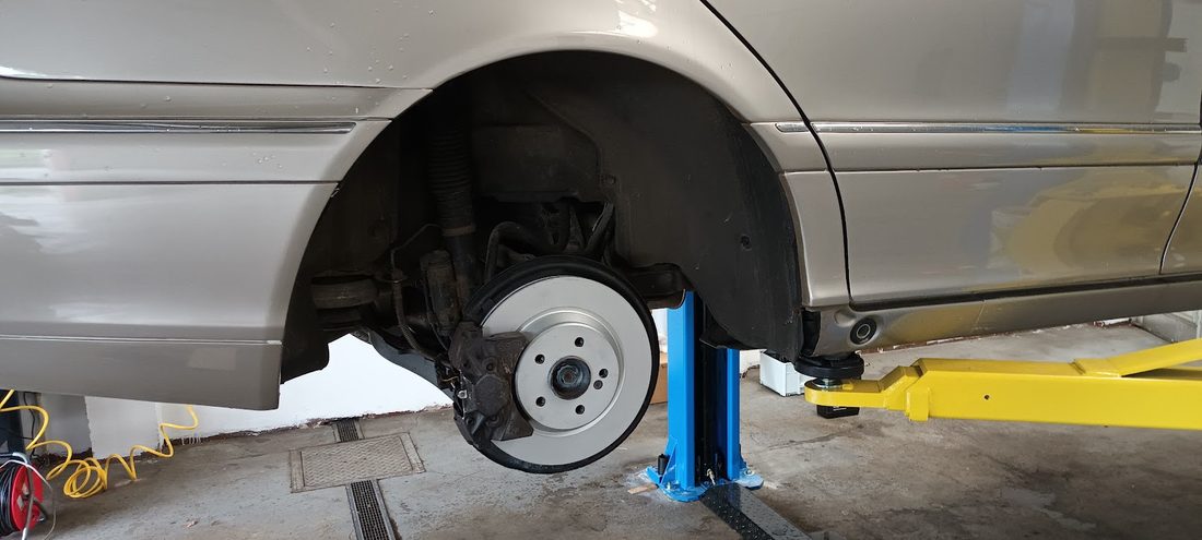 Auto na zvedáku se sundaným kolem, vidět je brzdový kotouč a třmen
